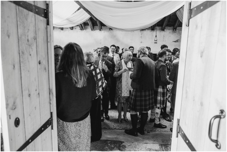 wedding guests at drinks reception in a rustic barn